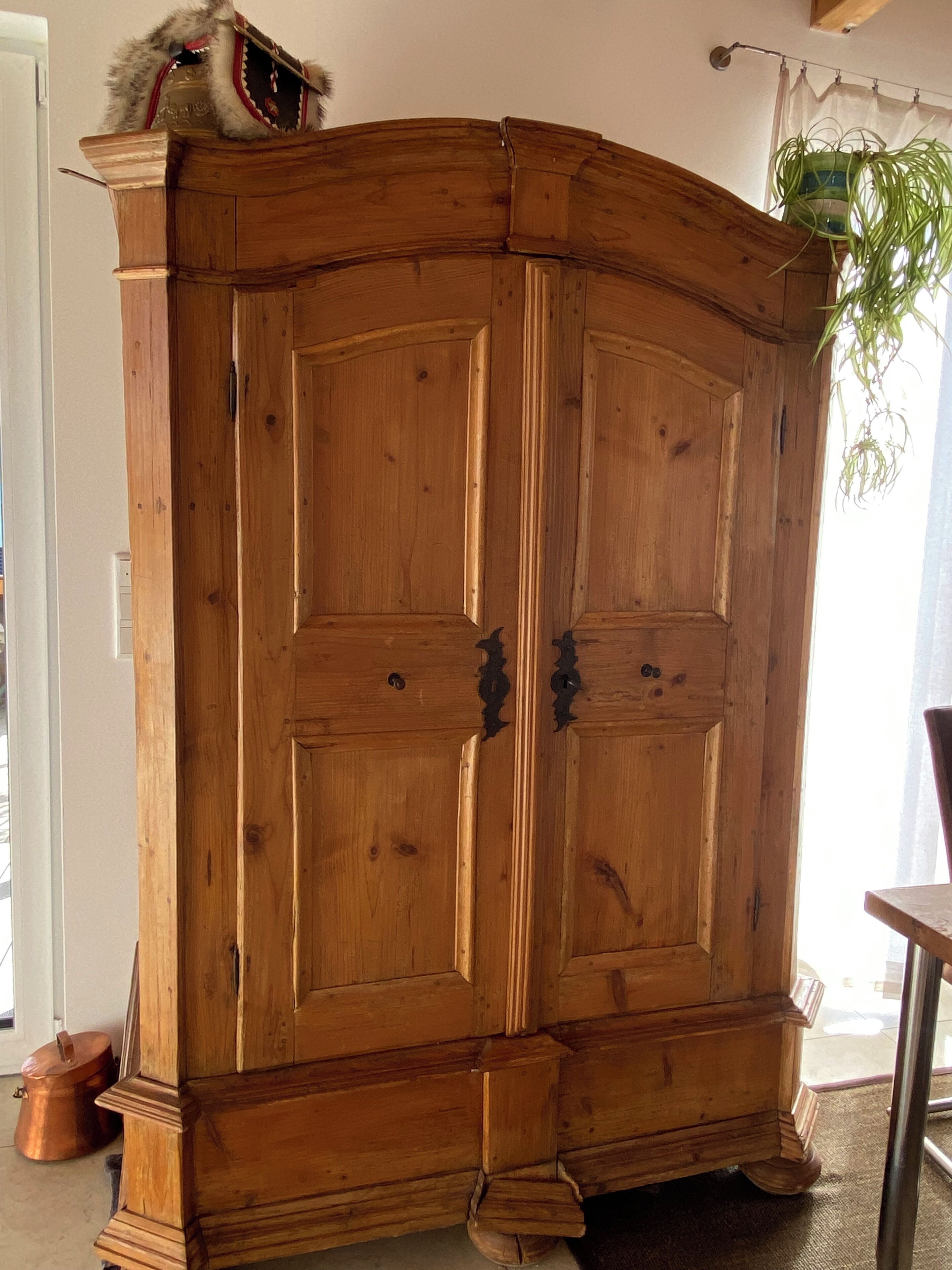 A wooden cabinet with a curved top and two doors.