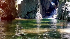 A clear, natural water body surrounded by rocky terrain.