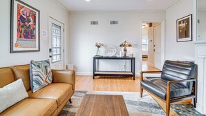 A living room with a brown leather sofa, a black leather armchair, a wooden coffee table, and a black console table with decorative items. - Spacious Memphis Retreat: 5 Mi to Downtown Beats! (Memphis)