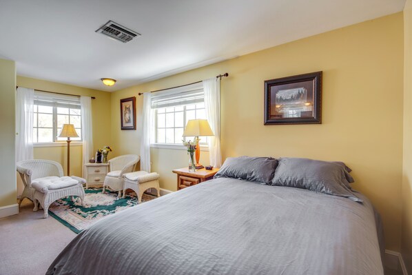 A bedroom with a large bed, two bedside tables, a chair, and a window with curtains. - Views + Trail Access: Scenic Montana Ranch Retreat (Emigrant)