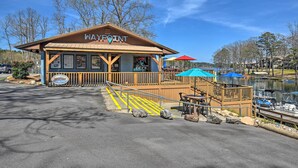 Un bâtiment en bois portant l’inscription « WAYPOINT », doté d’une terrasse, d’un panneau indiquant « BASECAMP » et offrant une vue sur un lac où se trouvent des bateaux.