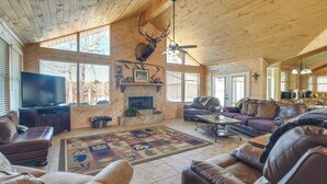 A spacious living room with a large wooden ceiling, a mounted deer head, a fireplace, leather sofas, and a television. - Fire Pit, Views: Lakefront Toledo Bend Retreat! (Many)