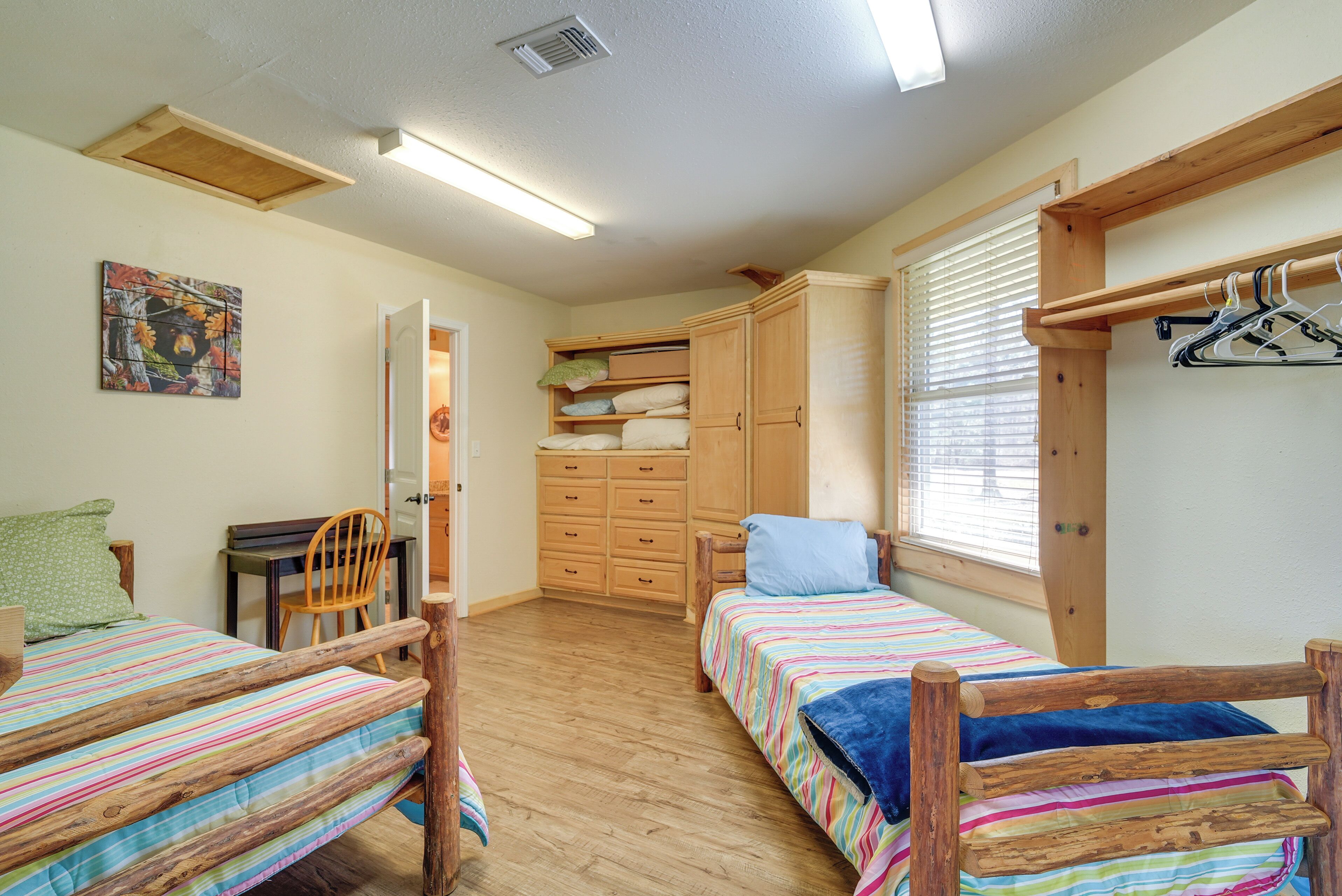 A bedroom with two wooden beds, a wooden wardrobe, a desk, and a chair.
