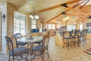 A spacious kitchen with wooden cabinets, a central island with bar stools, and a dining area with a round table and chairs.