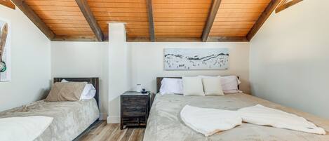Un dormitorio con dos camas, vigas de madera en el techo, una mesita de noche y un cuadro colgado en la pared.
