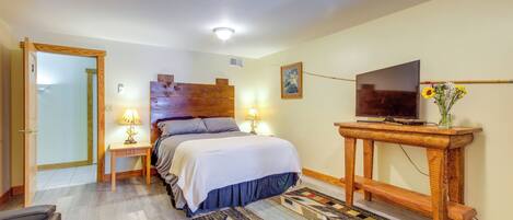 A bedroom with a bed, bedside lamps, a television on a wooden stand, and a patterned rug.