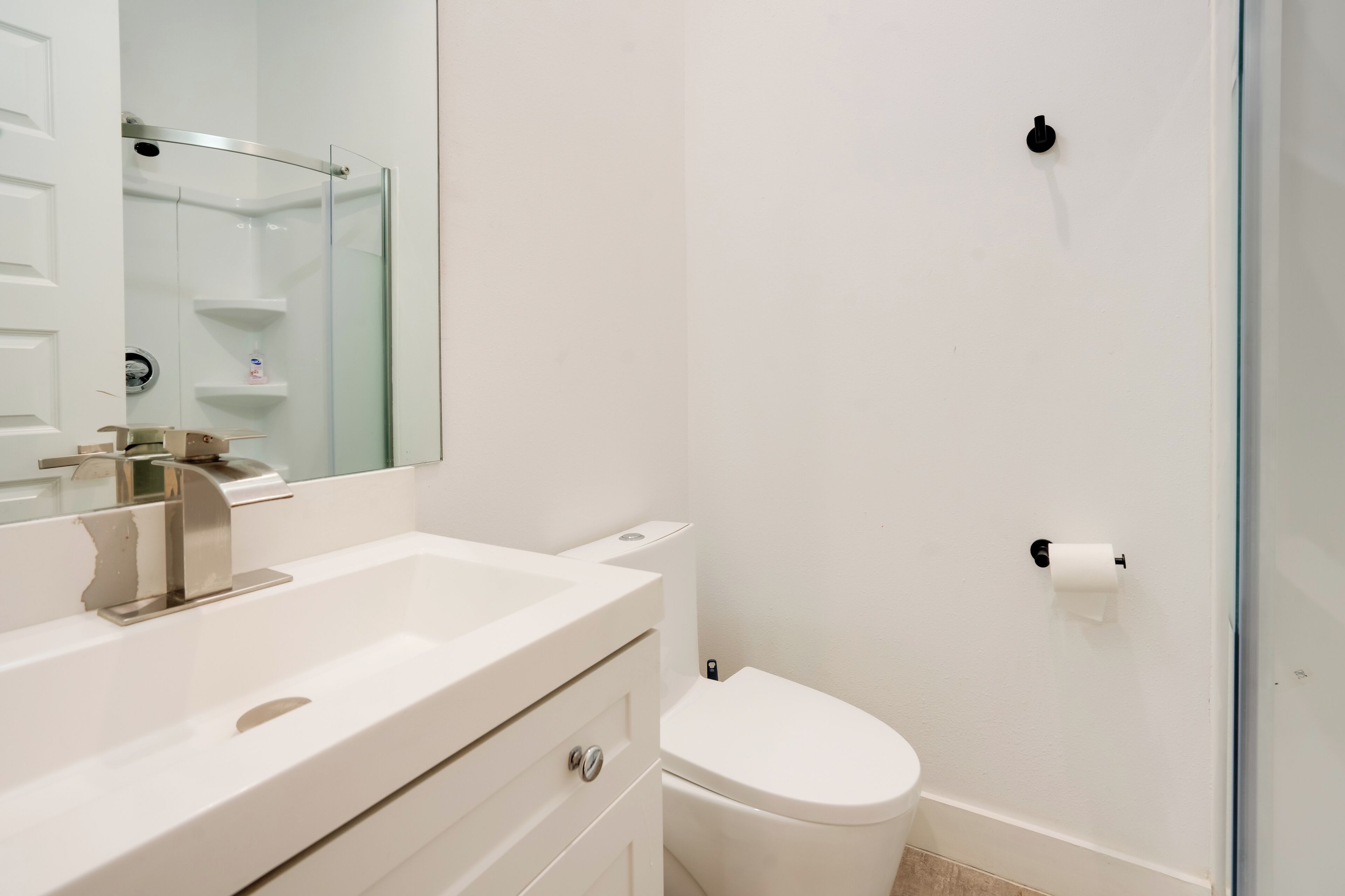 A modern bathroom with a white sink, mirror, and toilet.