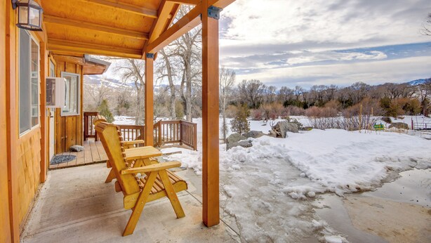 Une cabane en bois dotée d’un porche abrité, d’une table en bois et de chaises.