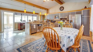 Une cuisine spacieuse dotée de meubles en bois, d’un grand réfrigérateur et d’un coin repas avec une table ronde et des chaises.