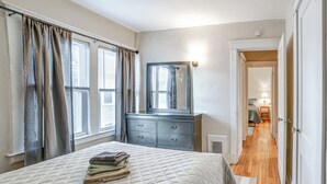 A bedroom with a bed, a dresser, a mirror, and a hallway leading to another room. - 1 Mi to Dtwn Binghamton: Apt w/ Covered Balcony! (Binghamton)