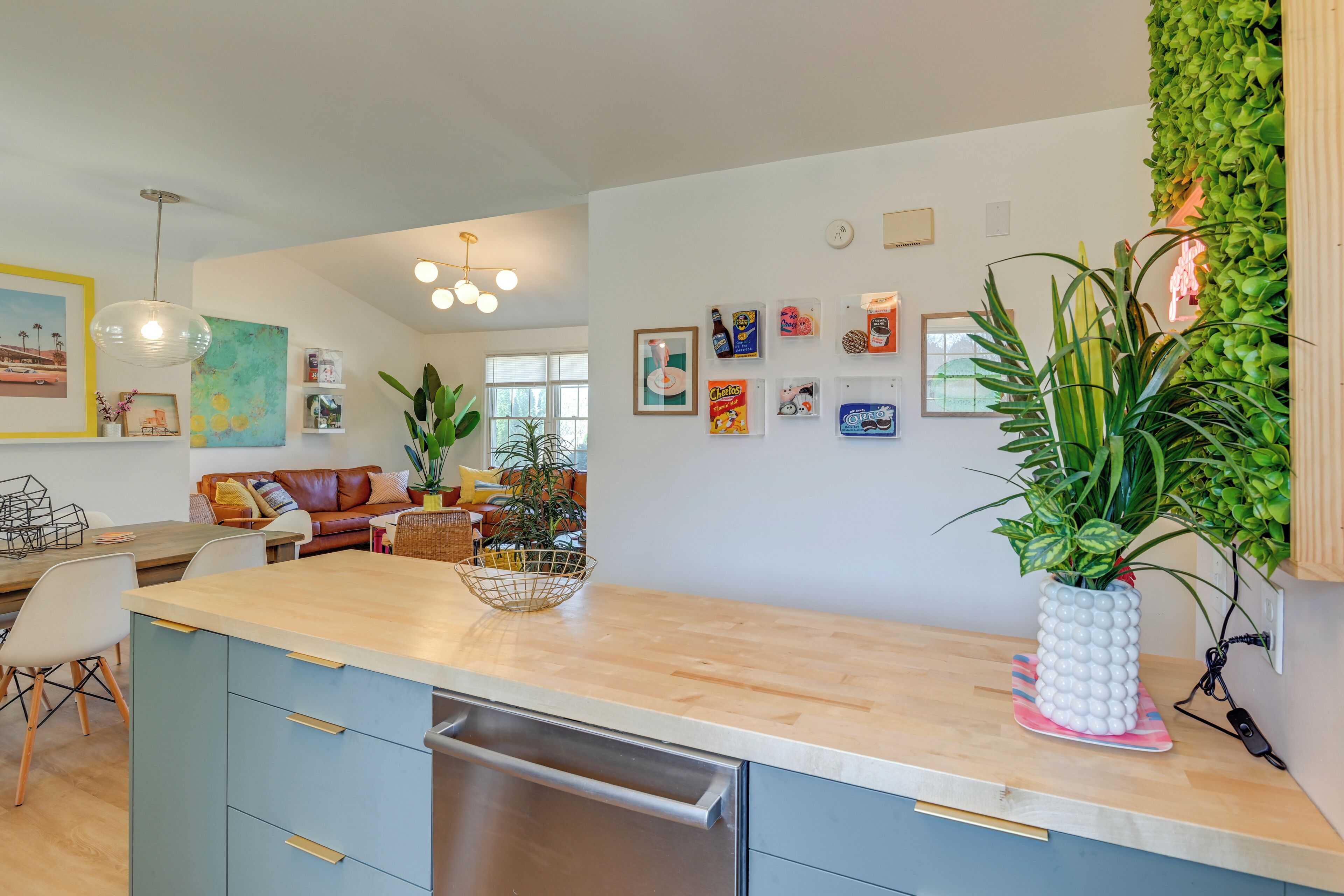 A modern kitchen with a wooden countertop, built-in dishwasher, and a dining area with a brown leather couch.