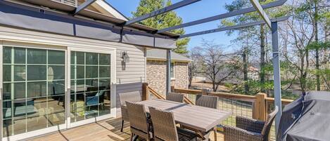 Una terraza exterior con mesa, sillas y una parrilla.