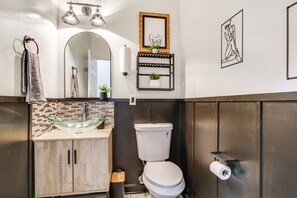 Une salle de bain moderne avec un lavabo en forme de bol en verre, des meubles en bois, des toilettes et un miroir.