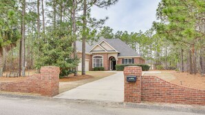 A single-story house with a brick facade, a front porch, and a driveway leading to a gated entrance. - 10 Mi to Augusta: Quiet Home w/ Patio & Yard! (Graniteville)