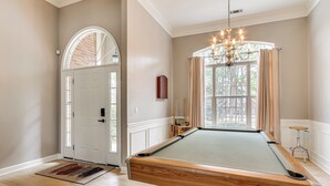 A pool table in a room with a door, a window with curtains, and a chandelier. - 10 Mi to Augusta: Quiet Home w/ Patio & Yard! (Graniteville)