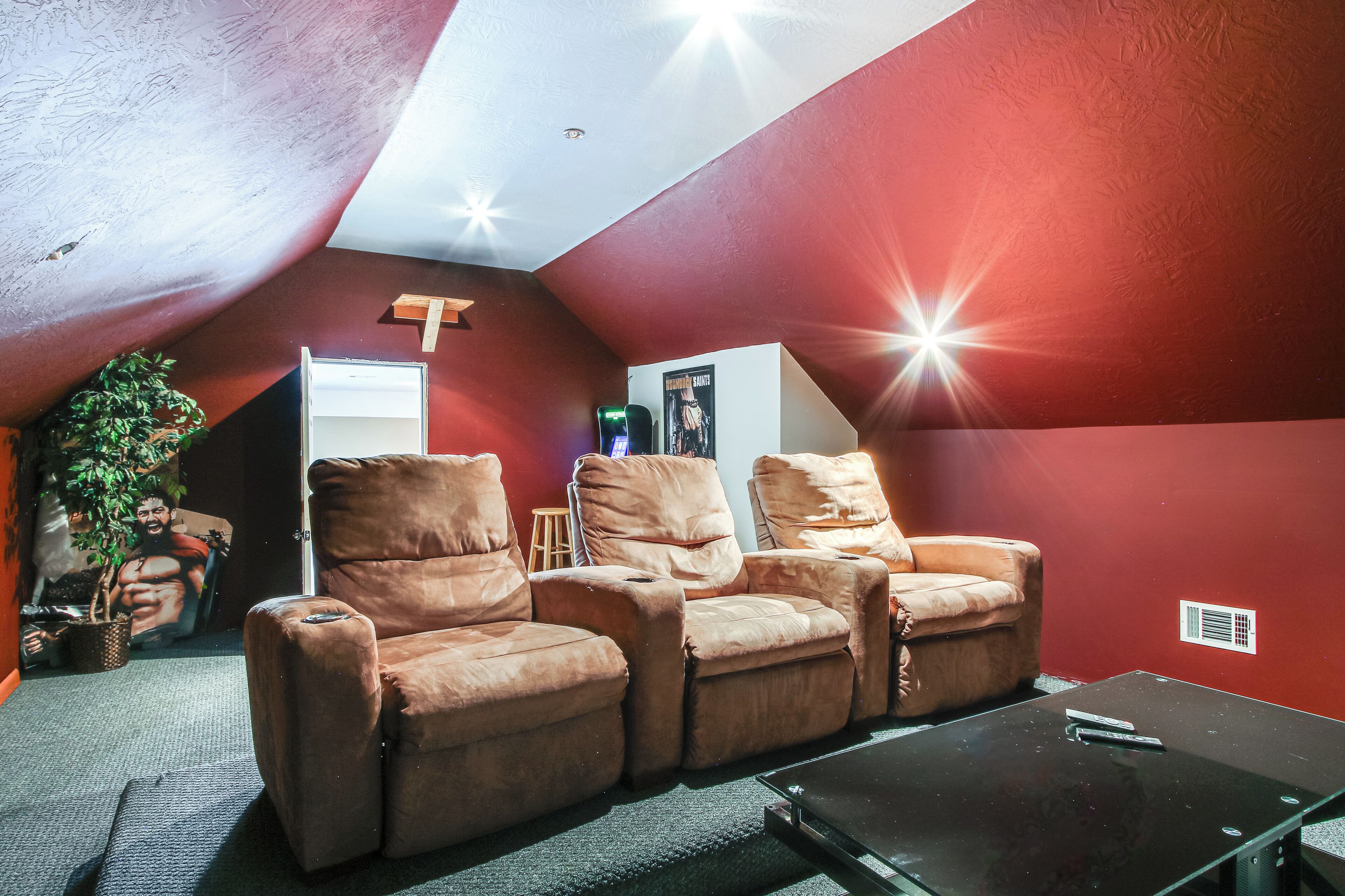 A cozy room with a red wall, a ceiling fan, and a reclining chair set.