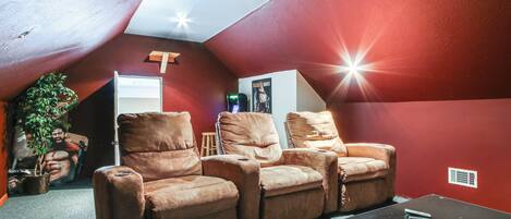 A cozy room with a red wall, a ceiling fan, and a reclining chair set.