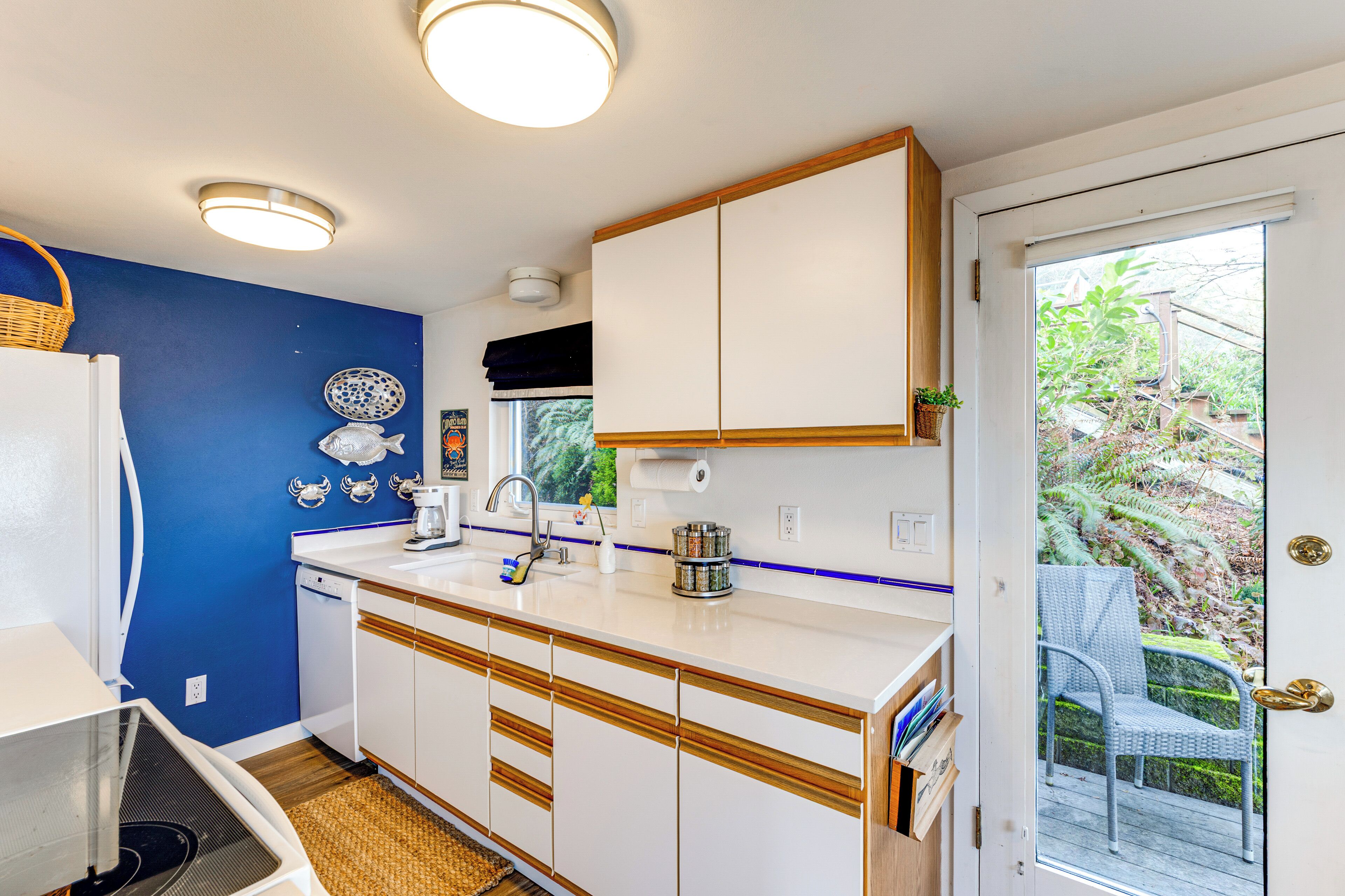 A compact kitchen with white cabinets, a sink, and a window overlooking a garden.