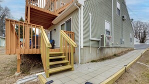A residential house with a wooden deck, a set of stairs leading to a porch, and a paved walkway. - Walk to Eastern Point Beach: Apt w/ Water View! (Groton)