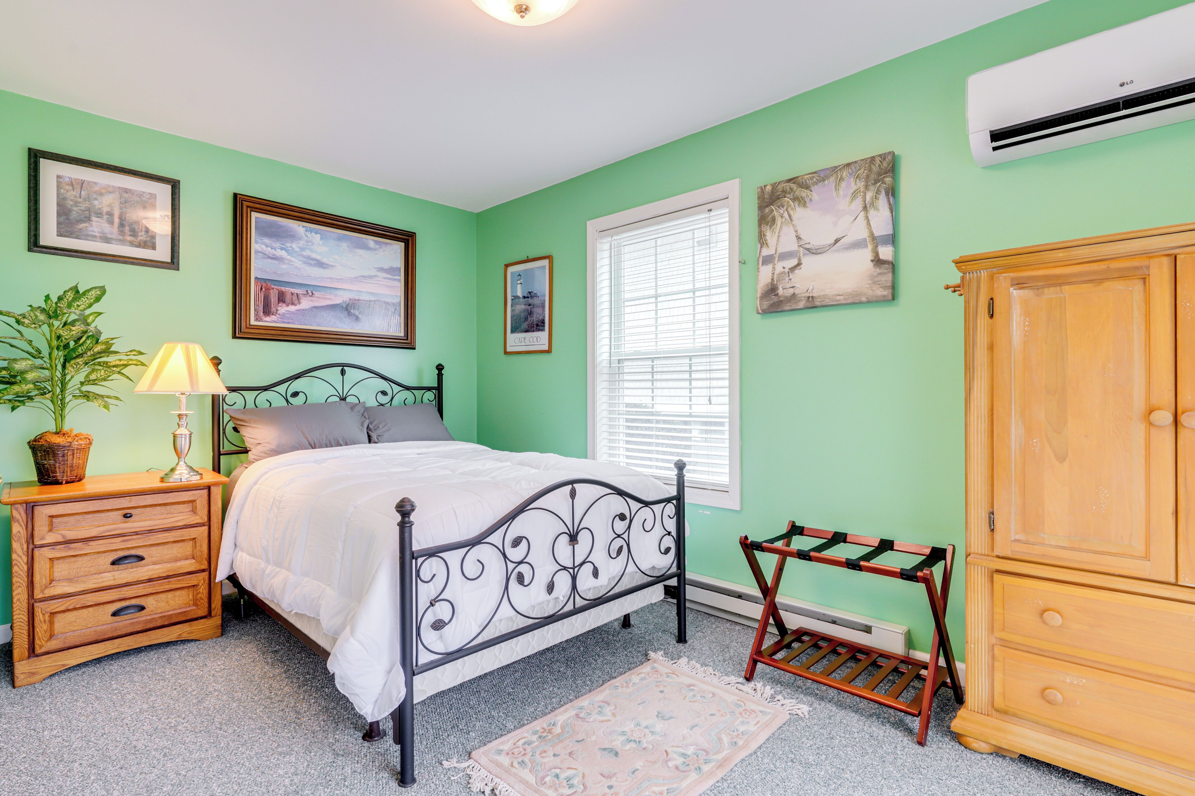 A bedroom with a bed, nightstand, dresser, and a window with blinds.