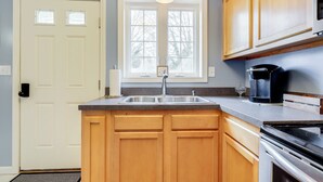 A kitchen with wooden cabinets, a stainless steel sink, and a built-in oven. - Walk to Eastern Point Beach: Apt w/ Water View! (Groton)