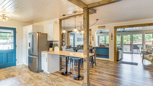 A spacious kitchen with a central island, wooden beams, and a view to the outside.