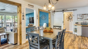 A dining area with a wooden table, grey chairs, and a dartboard.