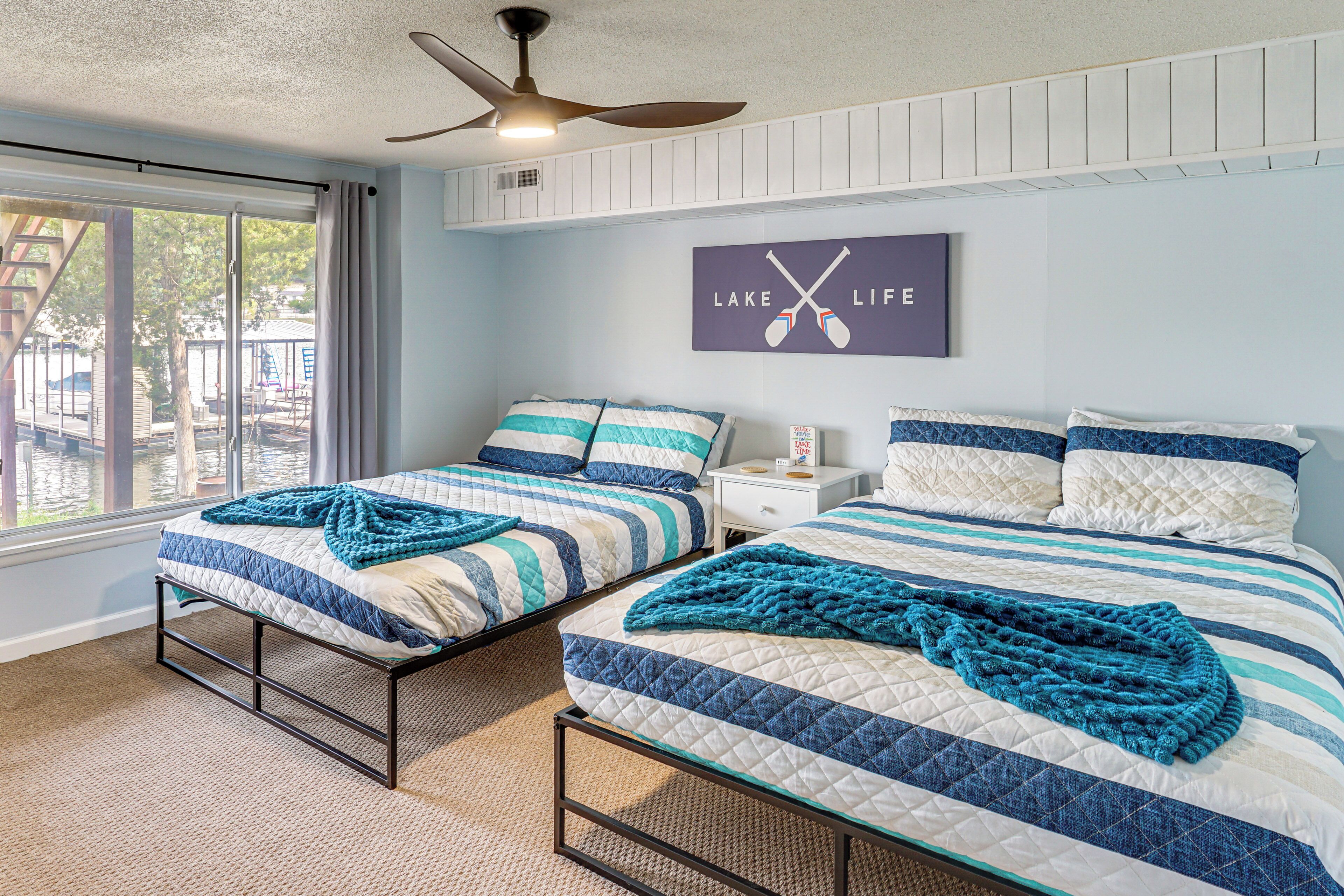 A bedroom with two beds, a ceiling fan, and a window with curtains.