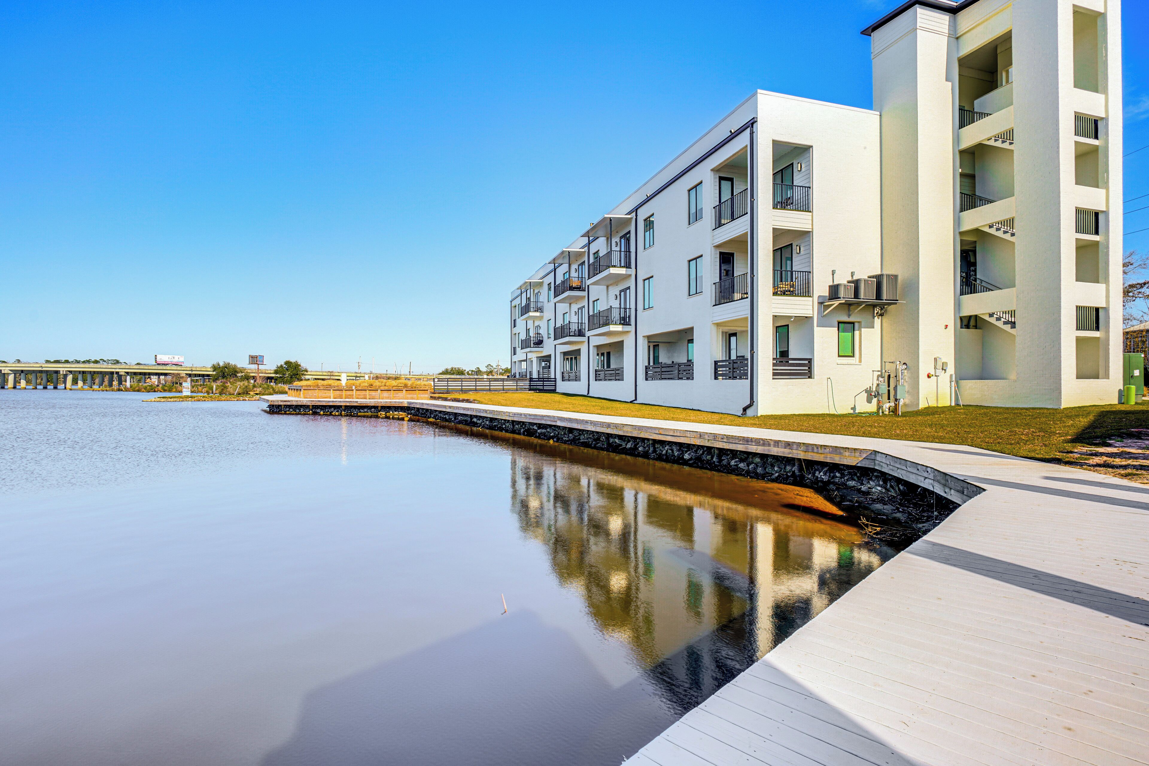 Un edificio de apartamentos moderno con balcones, vista al agua y una terraza de madera.