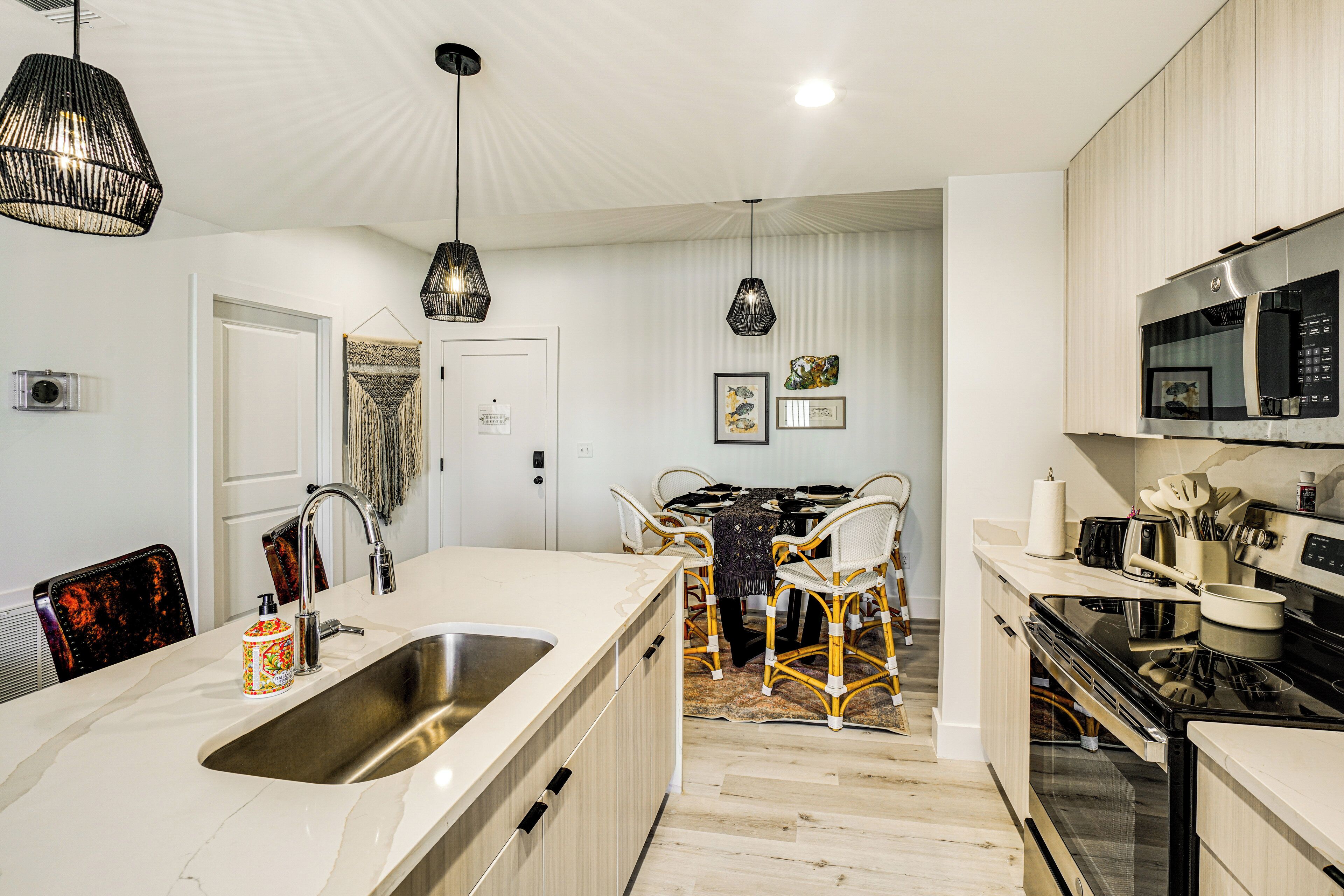 Una cocina moderna con una isla grande, electrodomésticos de acero inoxidable y un comedor con sillas de mimbre.