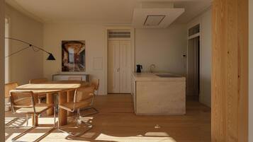 Een moderne keuken met een centraal eiland, een eethoek met een ronde tafel en stoelen, en uitzicht op een deur die leidt naar een andere kamer.