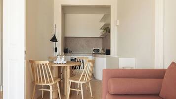 Un salon moderne avec un plancher en bois, un canapé rose et un coin repas comprenant des chaises en bois et une petite table.