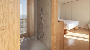A modern bathroom with a shower, wooden flooring, and a bed in the adjacent room. - LIOZ Lisboa (Lisbon)