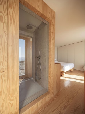 A modern bathroom with a shower, wooden flooring, and a bed in the adjacent room. - LIOZ Lisboa (Lisbon)