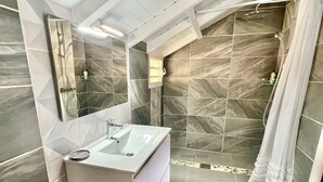 Un baño moderno con un espejo grande, un lavabo y una zona de ducha.