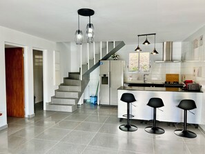 Eine moderne Küche mit einer zentralen Kochinsel, Barhocker und einer Treppe, die zu einer weiteren Ebene führt.