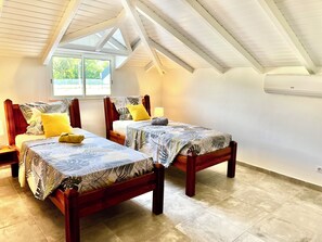 Ein Zimmer mit zwei Holzbettgestellen, einem Fenster und einem Deckenventilator.