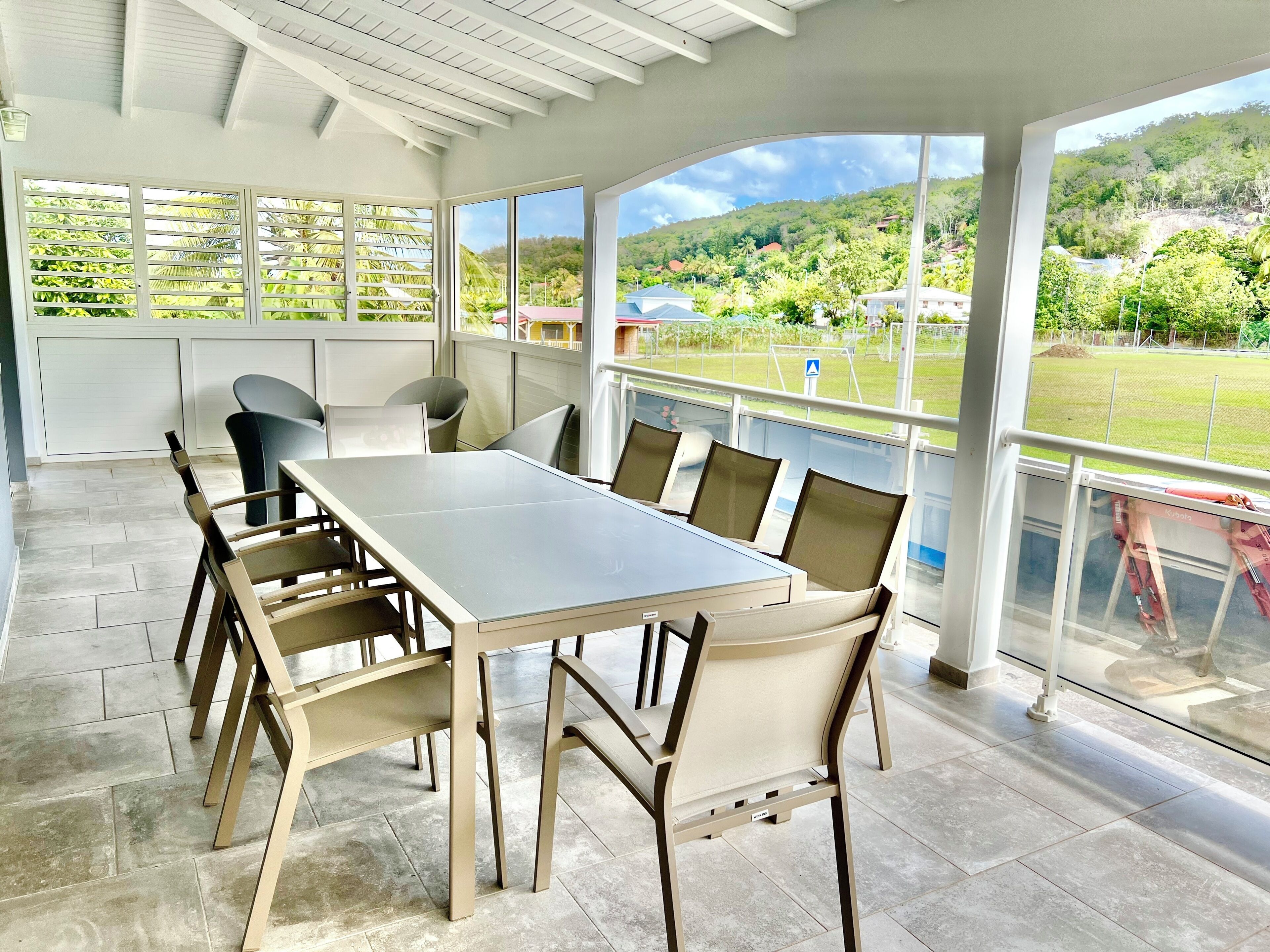 Una habitación amplia con una gran mesa y sillas, ventanas grandes que dan a un paisaje verde.