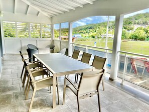 Une pièce spacieuse avec une grande table et des chaises, de grandes fenêtres donnant sur un paysage verdoyant.