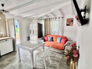 Une cuisine moderne avec un réfrigérateur blanc, une table à manger avec des chaises et un canapé agrémenté de coussins colorés.