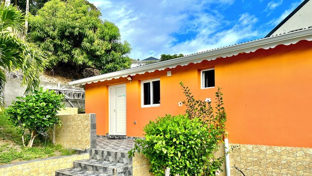 A house with a tiled entrance, a door labeled 'Zanzibar,' and a small window. - Zandoli Apartment. Bas Vent Estate. (Deshaies)