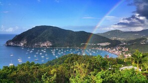 A coastal town with a mountainous backdrop and a visible rainbow.