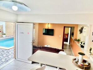 A modern living room with a pool, a sofa, a dining table, and a TV. - Colibri Apartment. Bas Vent Estate. (Deshaies)