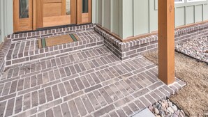 A building entrance with a wooden door, a nameplate, and a brick-paved area. - The Bella Muse - 3-Bedroom House W/ Hot Tub close to Bike Trails (Bella Vista)