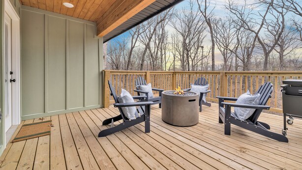 A wooden deck with Adirondack chairs and a fire pit. - The Bella Muse - 3-Bedroom House W/ Hot Tub close to Bike Trails (Bella Vista)