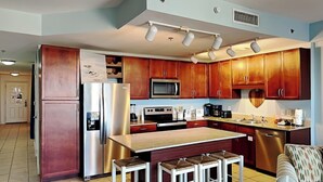 A modern kitchen with wooden cabinets, stainless steel appliances, and a central island with stools.