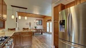 A modern kitchen with wooden cabinets, stainless steel appliances, pendant lighting, and a central island.