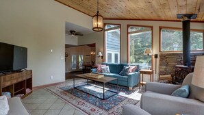 A spacious living room with a large flat-screen TV, a blue sofa, a coffee table, and a fireplace.