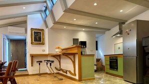 A modern kitchen with a wooden island, a refrigerator, and a dining area with chairs.