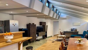 A modern living space with a dining area, kitchen, and entertainment setup.